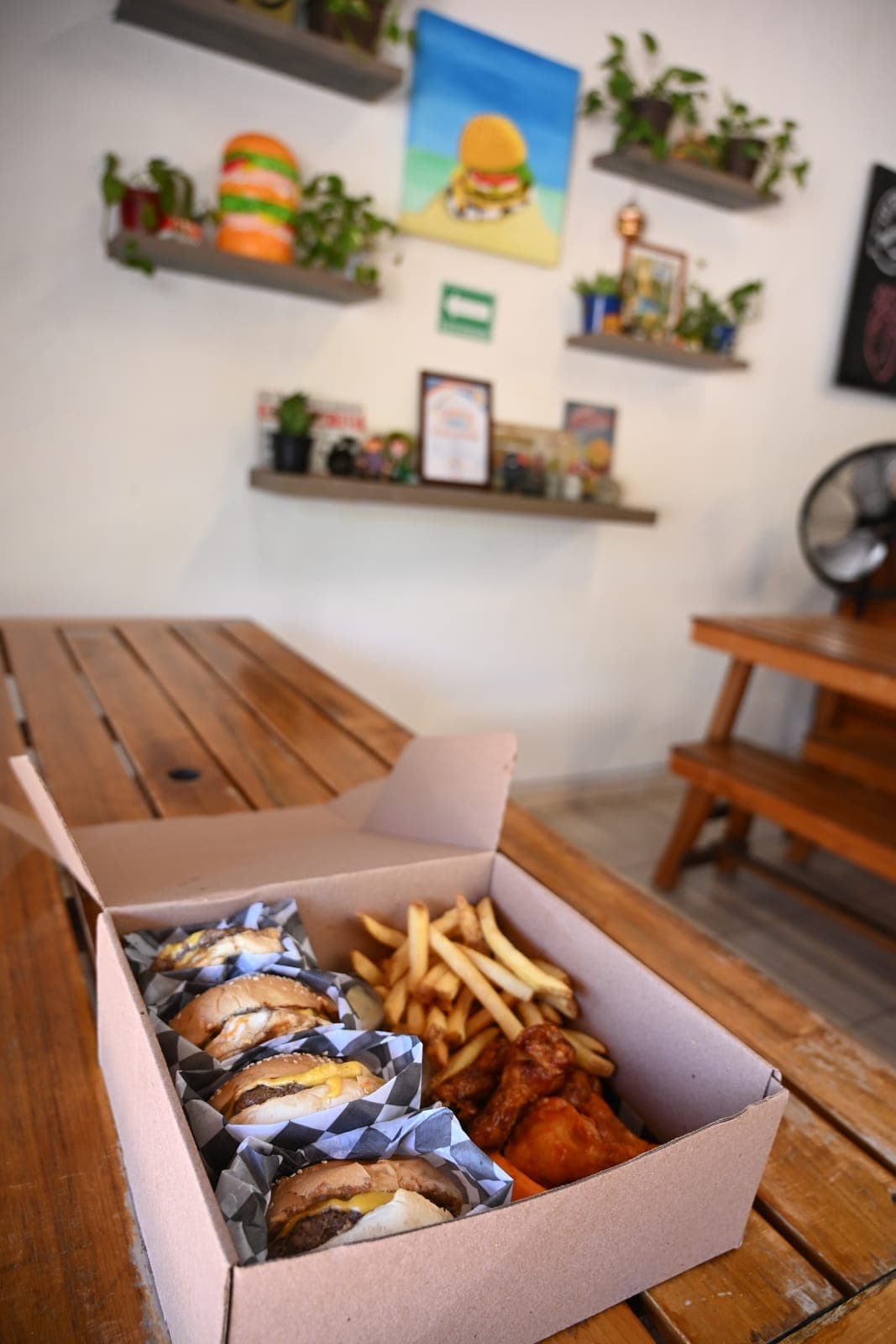 A box of burgers, fries and wings on a table inside The Burger Underground