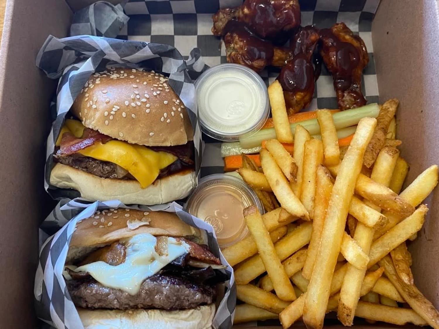 Two burgers, fries and wings in a Burger Underground box, on checkered paper
